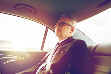 Image showing senior businessman driving on car back seat