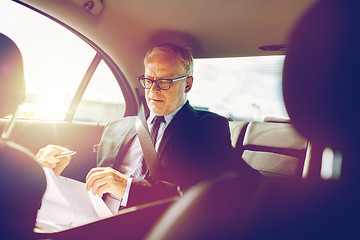 Image showing senior businessman with papers driving in car