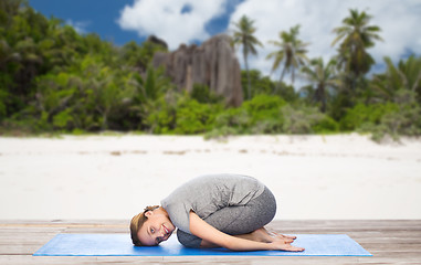 Image showing happy woman doing yoga in child pose on beach