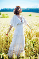 Image showing happy smiling middle-aged woman spinning in a white dress in a f