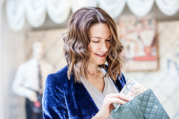 Image showing smiling middle-aged woman with a cheerful face counting cash