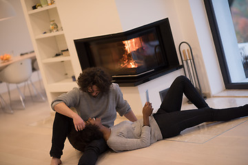 Image showing multiethnic couple using tablet computer on the floor