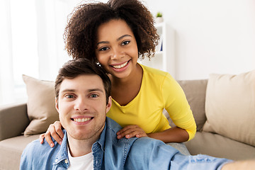 Image showing happy multiethnic couple taking selfie at home