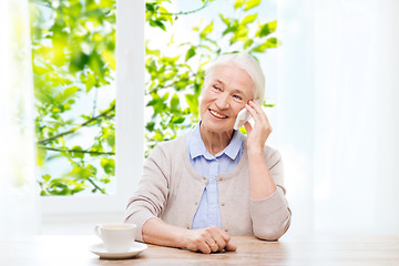 Image showing senior woman with smartphone calling at home