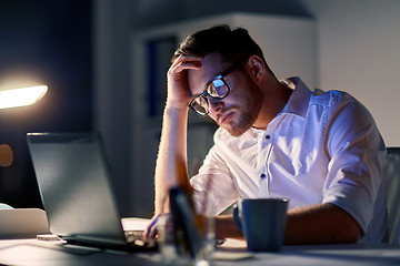 Image showing businessman with laptop thinking at night office