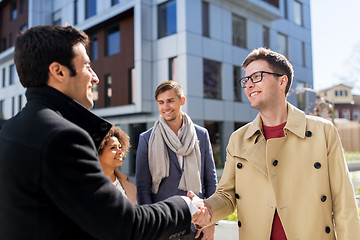 Image showing happy people shaking hands on city street