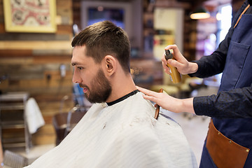 Image showing barber applying styling spray to male hair at shop