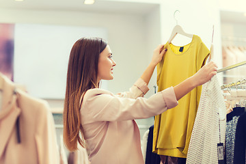 Image showing happy young woman choosing clothes in mall