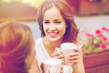 Image showing smiling young women with coffee cups at cafe