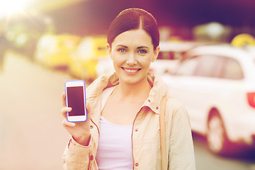 Image showing smiling woman showing smartphone over taxi in city