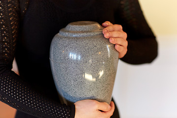 Image showing close up of woman with cremation urn at funeral