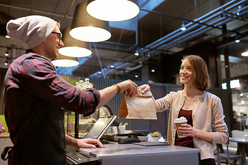 Image showing woman taking paper bag from seller at cafe