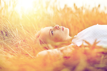 Image showing young woman lying on cereal field and dreaming