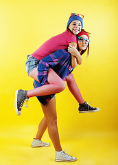 Image showing lifestyle people concept: two pretty young school teenage girls having fun happy smiling on yellow background 