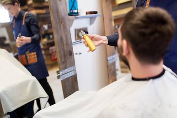 Image showing barber showing hair styling spray to male customer