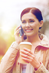 Image showing smiling woman with smartphone and coffee in park