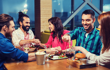 Image showing friends eating and tasting food at restaurant