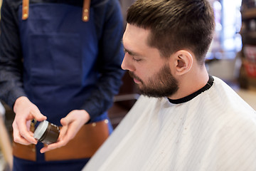 Image showing barber showing hair styling wax to male customer