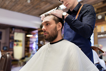 Image showing man and barber cutting hair at barbershop