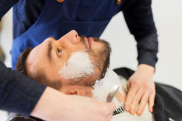 Image showing man and barber with straight razor shaving beard
