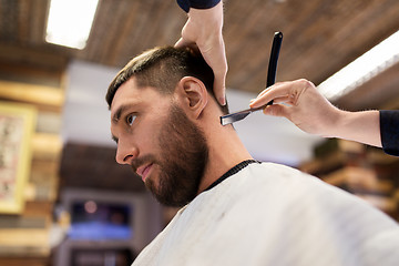 Image showing man and barber with straight razor shaving hair