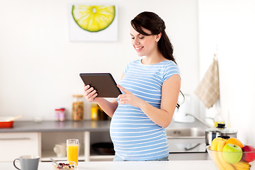 Image showing pregnant woman with tablet pc eating at home