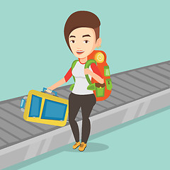 Image showing Woman picking up suitcase on luggage conveyor belt