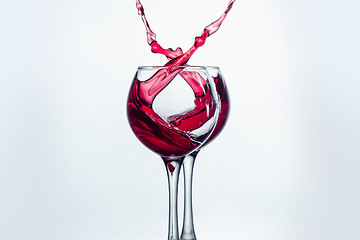 Image showing Two wine glasses in toasting gesture with big splashing.