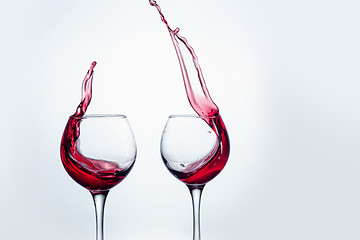 Image showing Two wine glasses in toasting gesture with big splashing.