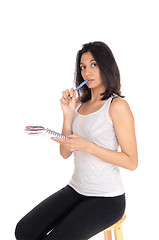 Image showing Woman talking nots with pen in mouth.