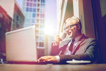 Image showing senior businessman with laptop drinking coffee