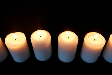 Image showing candles burning in darkness over black background