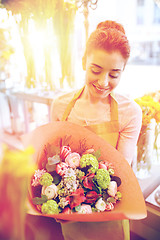 Image showing smiling florist woman with bunch at flower shop