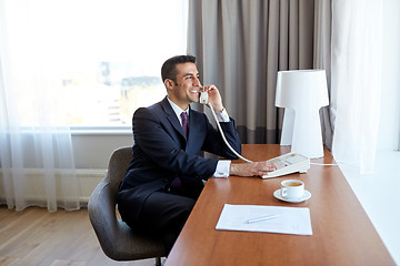 Image showing businessman calling on desk phone at hotel room