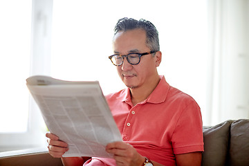 Image showing happy man in glasses reading newspaper at home