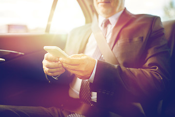 Image showing senior businessman texting on smartphone in car