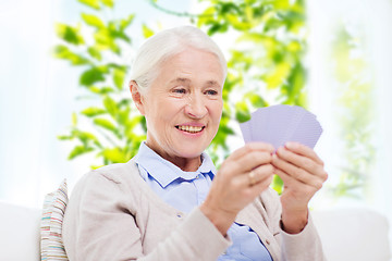 Image showing happy senior woman playing cards at home