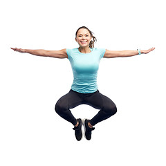 Image showing happy smiling sporty young woman jumping in air