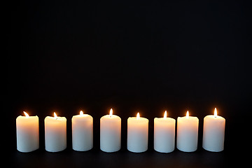 Image showing candles burning in darkness over black background