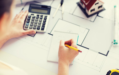 Image showing close up of hand on blueprint writing to notebook