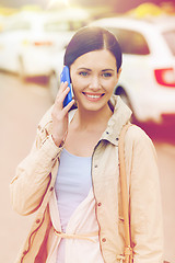 Image showing smiling woman with smartphone over taxi in city