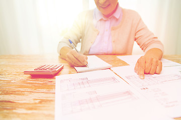 Image showing senior woman with papers and calculator at home