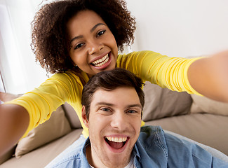 Image showing happy multiethnic couple taking selfie at home