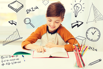 Image showing smiling, student boy reading book at home