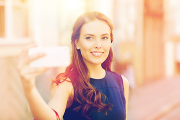 Image showing happy woman taking selfie with smartphone in city