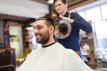 Image showing man and hairdresser with mirror at barbershop