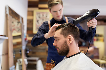 Image showing barber with fan drying male hair at barbershop