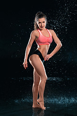 Image showing Young tanned fit woman with beautiful sporty buttocks and slim with water drops