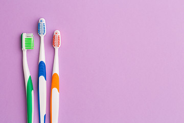 Image showing Photo of three multi-colored toothbrushes