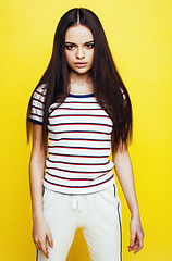 Image showing young pretty teenage woman emotional posing on yellow background, fashion lifestyle people concept 